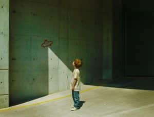 An illustration of a boy looking at a drawing of an alien spaceship on a wall