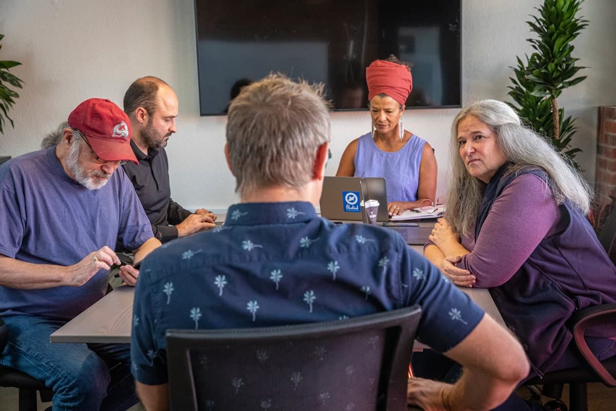 Five people sitting at a table in a boardroom, representing our skilled team of professionals who provide expert maintenance and support.